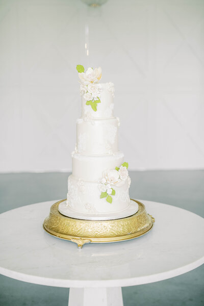 Beautiful white wedding cake atop a gold pedestal