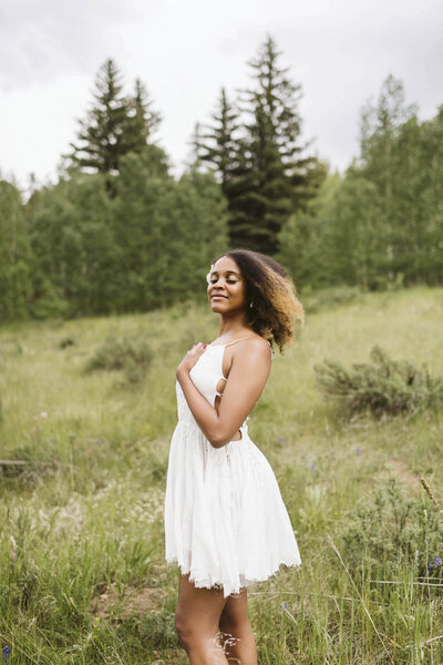 woman wearing a white dress standing in a field with her eyes closed