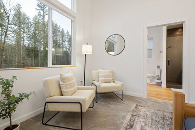 Bright sitting area with large windows and cream chairs