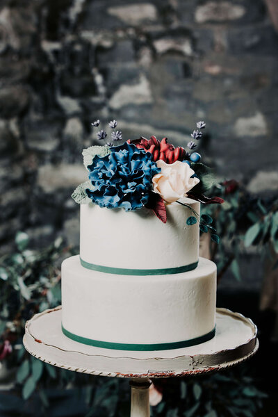 Two tier white textured wedding cake with navy sugar flowers