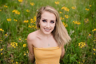 teen girl with blond hair in yellow striped tube top in field of yellow flowers