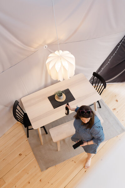 An overhead shot of a woman preparing the dining table at Hillhaus Domes, Quebec.