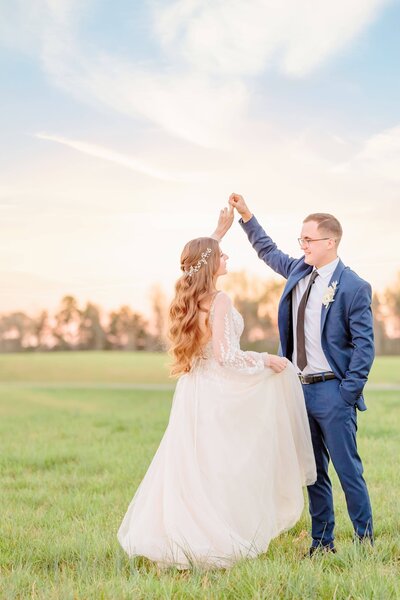 Anastasia and Max dance in the country grass at their Carolina wedding.
