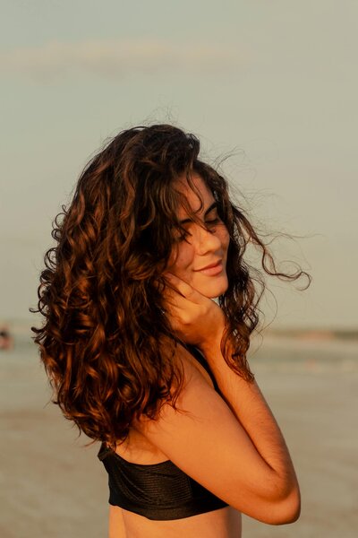 Smiling woman with curly hair on the beach at golden hour
