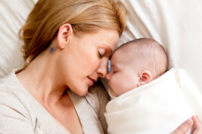 The joy of motherhood at a postnatal retreat as a mom and her newborn daughter sleep peacefully together, capturing a moment of happiness and bonding in Texas."
