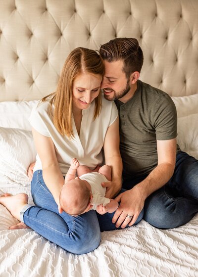 parents holding baby on bed for davis county newborn session