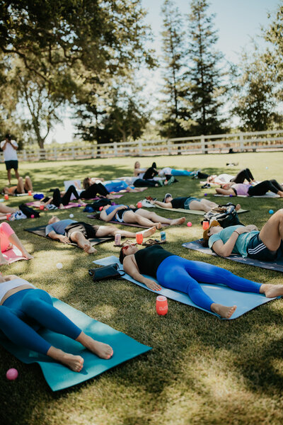 people laying on grass doing pilates