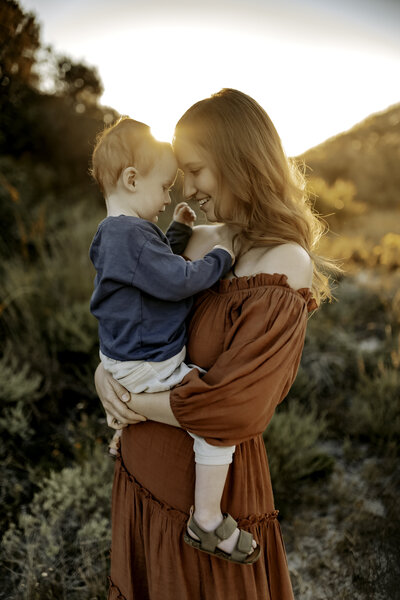 Family Photographer, a Mother holds her toddler boy  in a nature setting