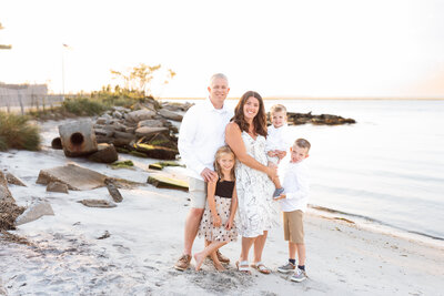 A family cuddles up for a golden hour portrait at the beach