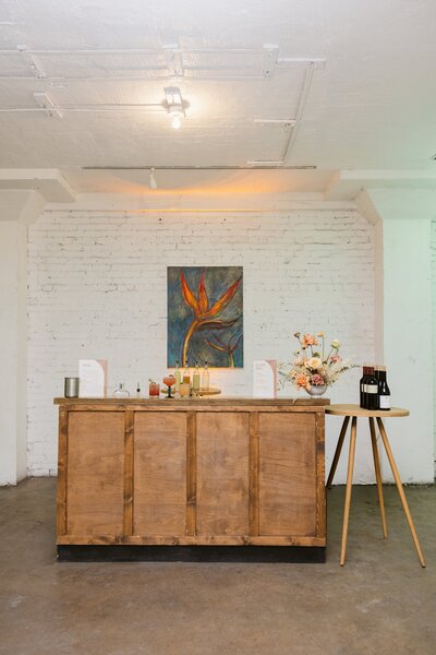 Wood cocktail bar styled with florals and custom signage for guests