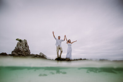 bride and groom jumping into water