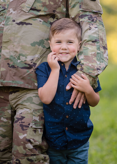 dad in military uniform with his arm around son with dimple
