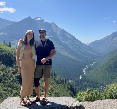 Becky & Brian, Yosemite elopement photographers stand at an overlook in Glacier National Park, Montana.