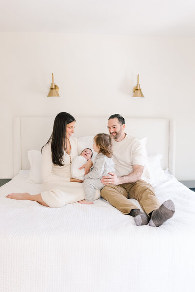 A couple stands close together during Newborn Photos in New Jersey and smile down at their baby.