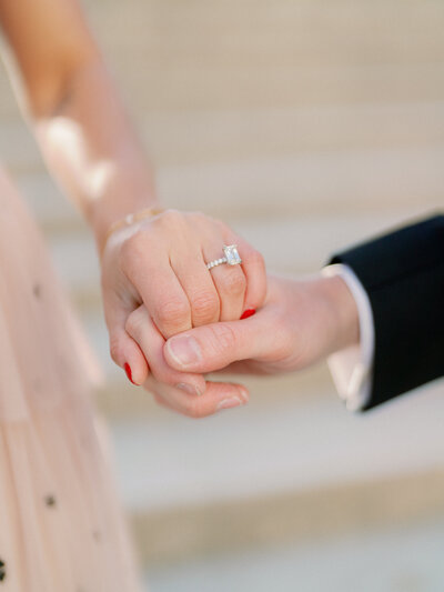 man and woman holding hands  with a diamond ring shimmering