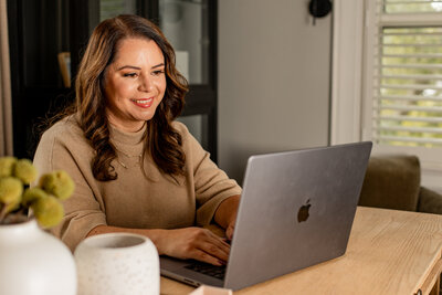 Woman smiling at computer screen in a posed photo in office