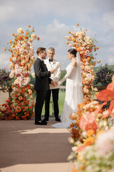 couple at wedding altar orange floral arch