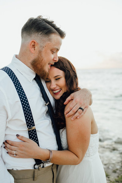 couple smiling & hugging next to ocean