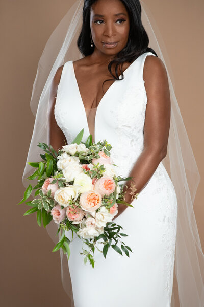 bride wearing a chapel length veil and holding a white and blush bouquet