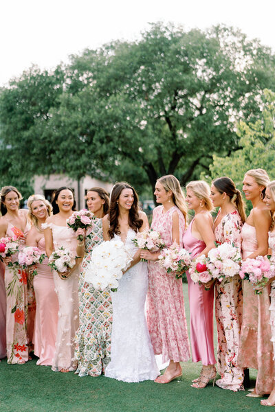 Bride surrounded by smiling bridesmaids in pink dresses