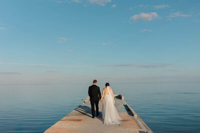 The newlyweds enjoy a sunset stroll on a pier during their St. Pete elopement, captured in this whimsical and dreamy portrait.