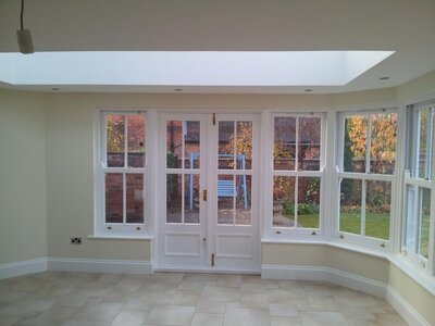 Bright conservatory orangery interior with tiled floor and white-framed windows.