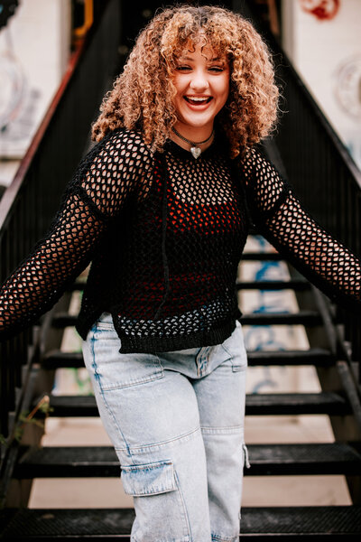 High School girl standing on metal staircase for urban downtown Denver Senior photos.