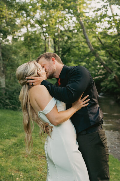 Bride lovingly embraces groom, viewed through the window of a green vintage truck