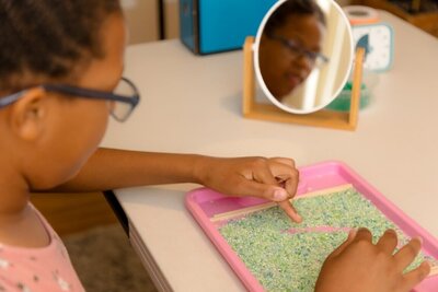 struggling reader tracing letters in rice for multisensory input