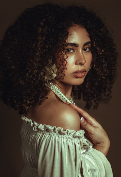 Curly brown hair, white pearl necklace, circle earrings