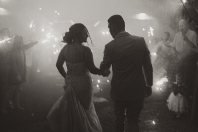 Photo of a coupl running together through tunnel of sparklers during their wedding.