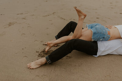 couple hugging while laying on the beach