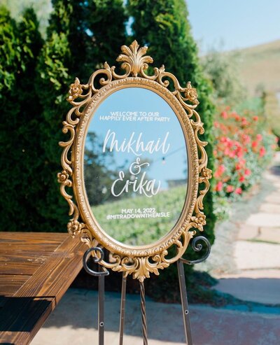 Ornate oval mirror rental with welcome message in calligraphy for a wedding