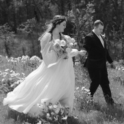 Bride & Groom walking hand in hand in Oregon wildflowers