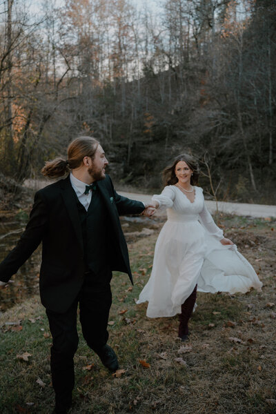 photo of bride and groom running while holding hands