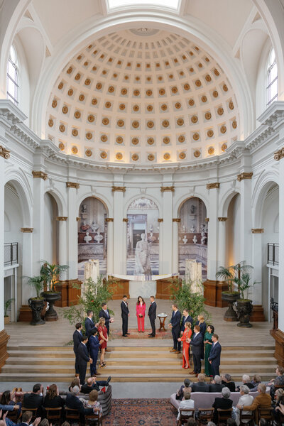 Grooms at altar of wedding ceremony in large domed building