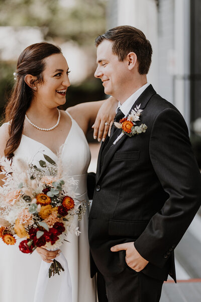 Orlando Wedding Photographer Joanna from Four Loves Photo and Film, and her husband Cole in a photo from their own wedding day. Joanna has her arm casually propped on Cole's shoulder as they look at each other and smile.