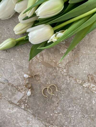 Tulips and earrings laying on a marble table