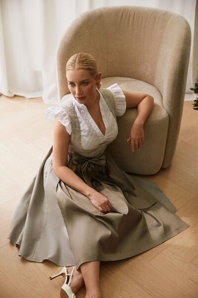Stilvolles Dirndl-Outfit für Frauen mit schimmerndem Rock in Beige, kombiniert mit Seidenschürze und kurzer Dirndlbluse. Perfekte Kombination aus traditionellem Charme und moderner Eleganz – bayerische Designertracht von Monaco Spatzl aus München.