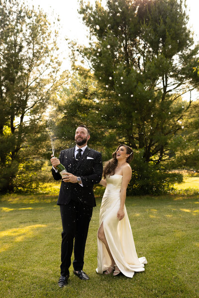 a bride and groom celebrate by popping champagne on their wedding day in Bracesville, Ohio. A true love story. Friends of more than 20 years before dating. And now finally happily married! Photographed by Aaron Aldhizer