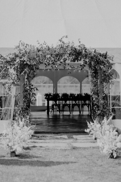 Black and white photo of wedding arch lined with flowers