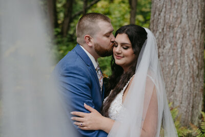 A man embracing a woman wearing a long cathedral style veil. 