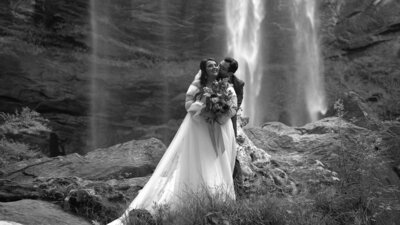 A Bride and groom are in front of a waterfall