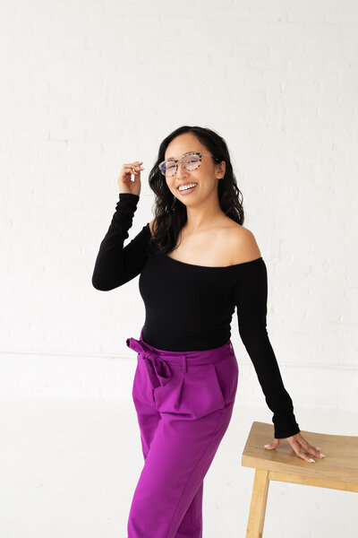 Anh Nguyen, NYC graduation photographer, smiling at the camera during a studio portrait session while playing with her hair.