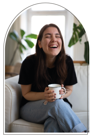 laughing young woman with a mug in her hands, sitting on a white sofa