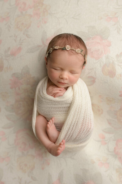 newborn baby girl swaddled on floral backdrop