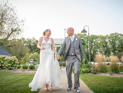 excited wedding couple run toward photorapher