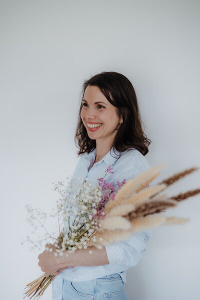 Portrait von einer Frau für ein Business Shooting mit Blumen im Arm