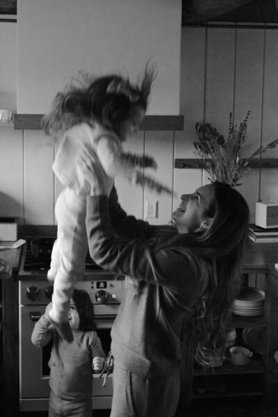 Mother throwing her daughter in the air in her kitchen during a family session in Lexington SC