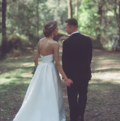 Couple holding hands while walking in the forest after their wedding ceremony shot on 120 film
